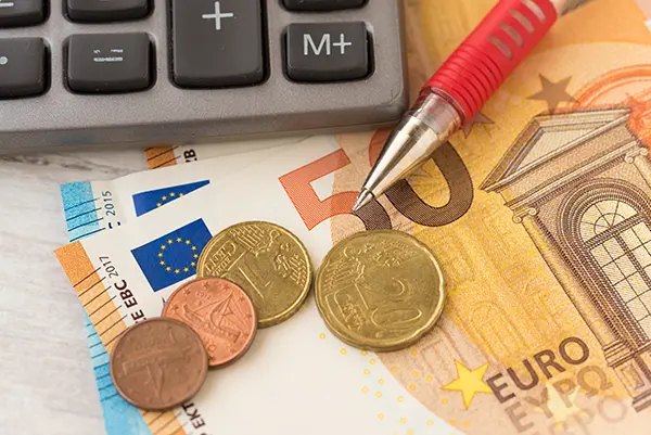 Calculator, euro banknotes, and coins on a table.