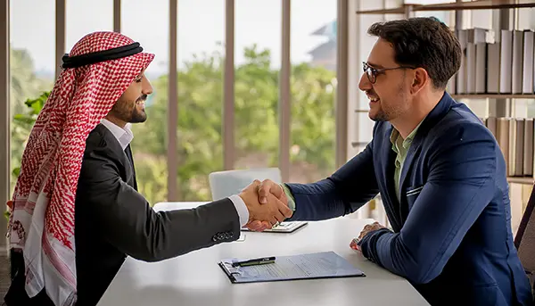 Two businessmen shaking hands at a meeting.